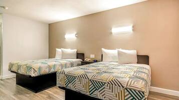 Habitación doble con dos camas, una mesita de noche y una lámpara fijada a la pared.