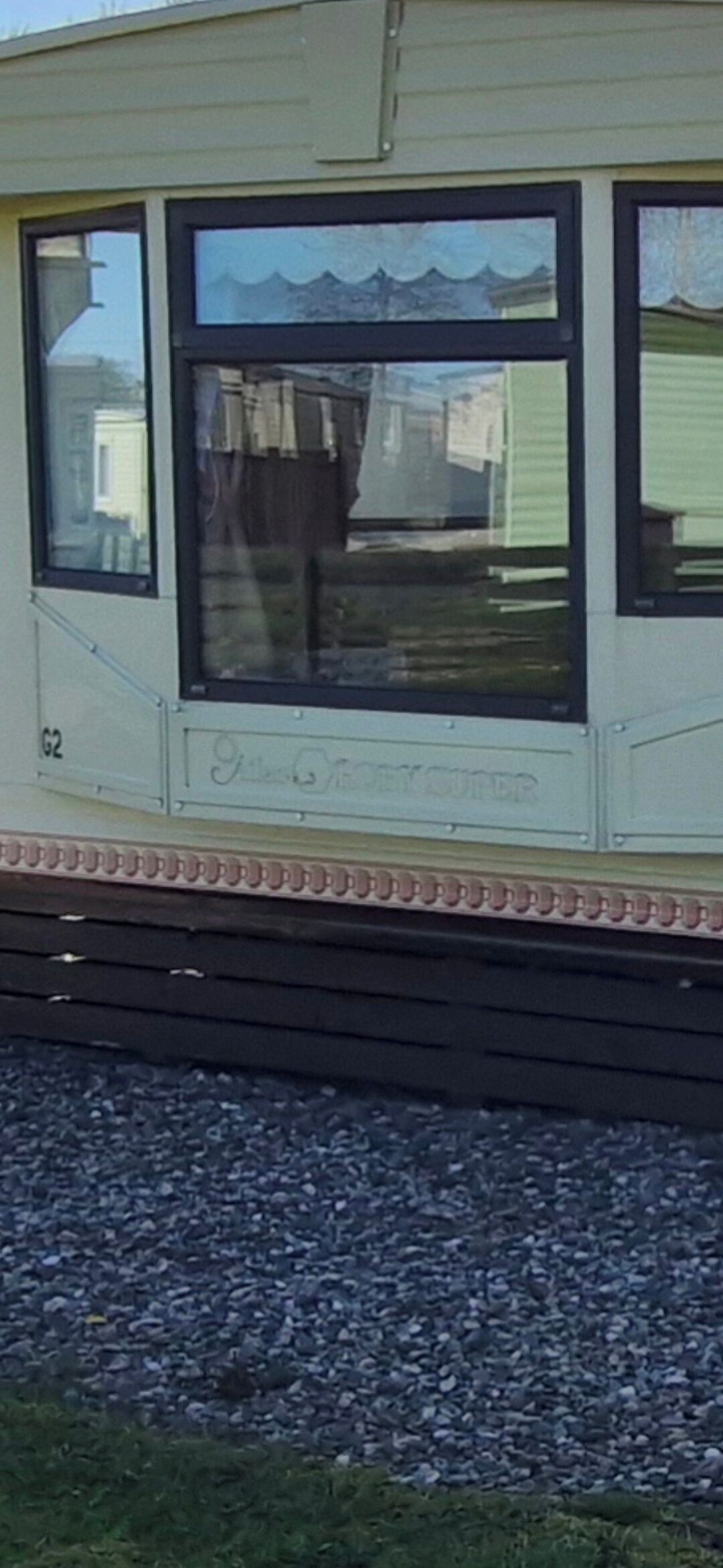 A caravan with a large window, a number 'G2' on the side, and a small balcony area.