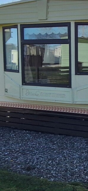 Une caravane dotée d’une grande fenêtre, du numéro « G2 » peint sur le côté et d’un petit balcon.