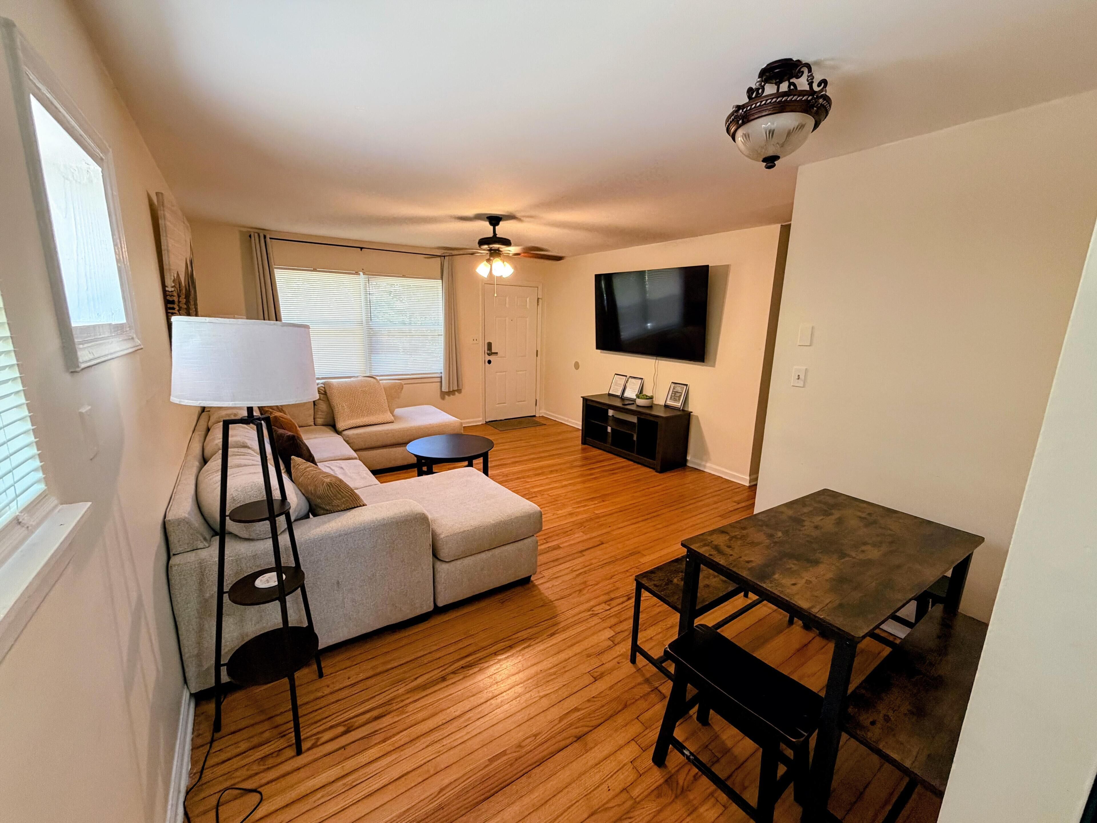 A living room with a sofa, a coffee table, a TV, and a dining table.