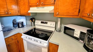 A kitchen with wooden cabinets, a stove, a microwave, and a toaster. - Parthenia's Love Shack (Durham)
