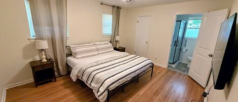 A bedroom with a bed, bedside tables, a ceiling fan, and a door leading to a bathroom.