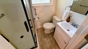 A bathroom with a toilet, sink, and shower. - Parthenia's Love Shack (Durham)