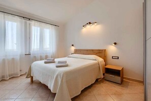 A neatly arranged bedroom with a bed, bedside table, and a wall-mounted light fixture. - Holiday Apartment with Sea View (Vodnjan)