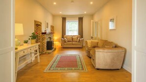 A living room with a fireplace, two sofas, a coffee table, and a rug. - The Stone House Sleeps 10 with Parking (Galway)