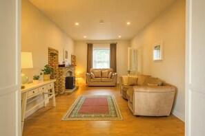 Ein Wohnzimmer mit Kamin, zwei Sofas, einem Couchtisch und einem Teppich.