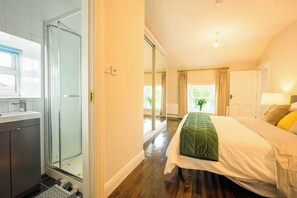 Ein Hotelzimmer mit Dusche, einem Bett mit grüner Bettdecke und Blick ins Freie.