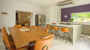 A modern kitchen with a wooden dining table, bar stools, and a built-in island. - The Stone House Sleeps 10 with Parking (Galway)