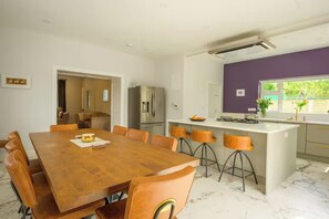 Eine moderne Küche mit Holztisch, Barhocker und einer integrierten Kücheninsel.
