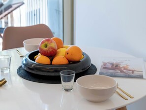 Ein Tisch mit Obstschale, einem Wasserglas, einer Schüssel und einer Zeitschrift.
