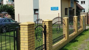 Ein Wohngebäude mit einer beigen Fassade, einem blauen Schild und einem schwarzen schmiedeeisernen Zaun.