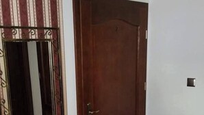 Ein Zimmer mit Holztür, einer Bank, einem Spiegel und fliesenbelagtem Boden.