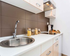 Eine moderne Küche mit Spüle aus Edelstahl, einer weißen Arbeitsplatte und einer braunen Rückwand.