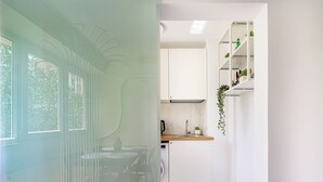 A modern kitchen with white cabinets, a wooden countertop, and a hanging plant. - Deda Studio w. Smart TV · AC · washing machine (Bucharest)