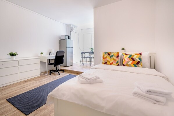 A modern hotel room with a bed, a desk, a chair, a small table, and a refrigerator. - Deda Studio w. Smart TV · AC · washing machine (Bucharest)