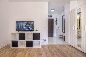 A modern living room with a flat-screen TV, a white entertainment unit, and a wooden floor. - Deda Studio w. Smart TV · AC · washing machine (Bucharest)