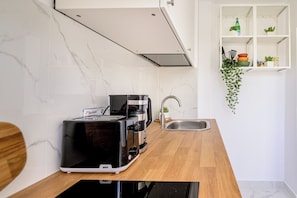 Une cuisine équipée d’un grille-pain, d’une machine à café, d’un évier et d’une plante suspendue.