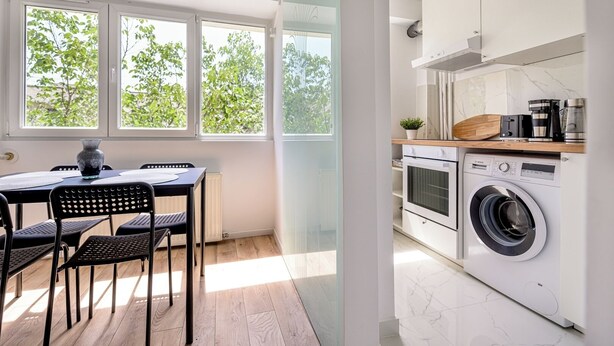 A modern kitchen with a washing machine, a coffee maker, and a dining area with a table and chairs. - Deda Studio w. Smart TV · AC · washing machine (Bucharest)