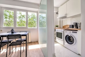 Une cuisine moderne équipée d’un lave-linge, d’une machine à café et d’un coin repas avec une table et des chaises.