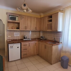 A kitchen with wooden cabinets, a microwave, a sink, and a refrigerator. - Beautiful 2-bedroom apartment with AC in charming Fethiye (Fethiye)