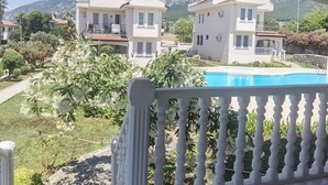 Um bairro residencial com casas, uma piscina e uma varanda com balaustrada branca.