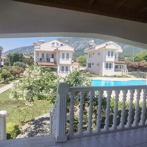 A residential area with houses, a swimming pool, and a balcony with a white balustrade. - Beautiful 2-bedroom apartment with AC in charming Fethiye (Fethiye)