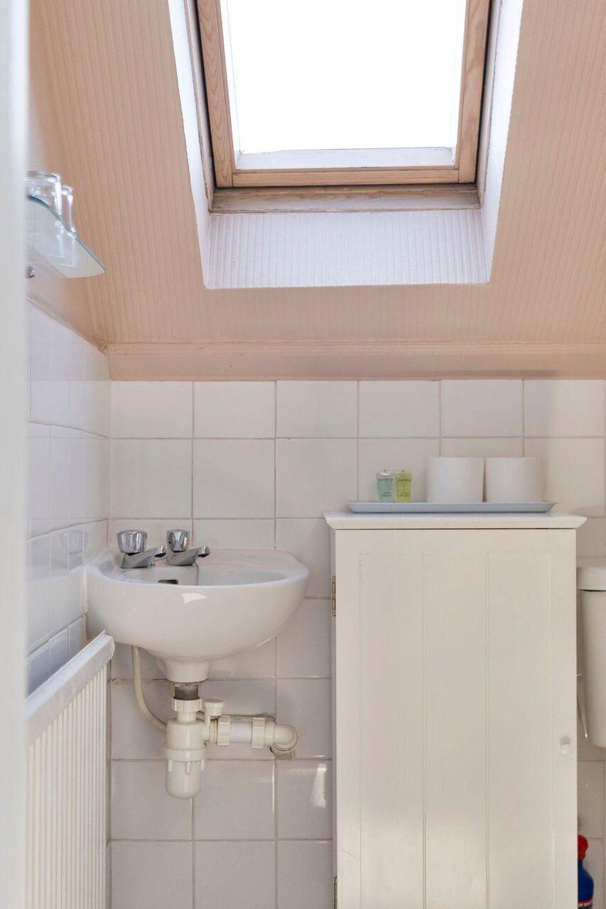 Une salle de bain avec un puits de lumière, un lavabo, un meuble et un radiateur.