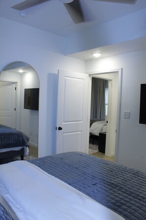 A bedroom with a bed, a door leading to another room, and a ceiling fan. - Luxury 2BR Near Medical District - Gated Parking & Sleeps 6 (Memphis)