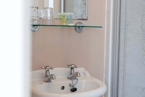 A bathroom with a white sink, two faucets, and a glass shelf above the sink. - GuestReady - Bright Studio in Leith, Edinburgh (Edinburgh)