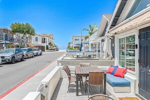 A street with parked cars, outdoor seating, and a building with large windows. - Beach House w/ AC, Steps to Sand, 38th St Park, and the Boardwalk (Newport Beach)