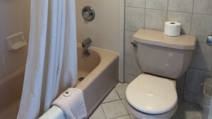 Een badkamer met een bad, toilet en douchegordijn.