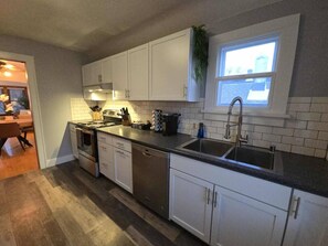 Eine moderne Küche mit weißen Schränken, Edelstahlgeräten und einem Fenster über der Spüle.