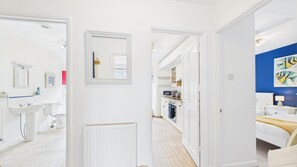 Een moderne hotelkamer met badkamer, kitchenette en een slaapkamer met een bed en nachtkastje.
