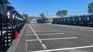Un estacionamiento con filas de vagones de tren negros y un cielo despejado.