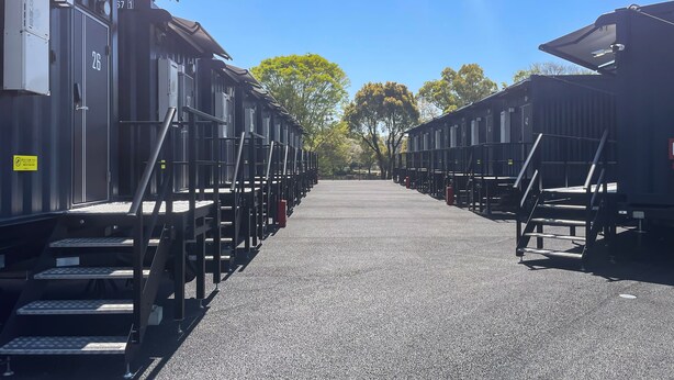 Filas de cabañas portátiles con escaleras metálicas bajo un cielo despejado.