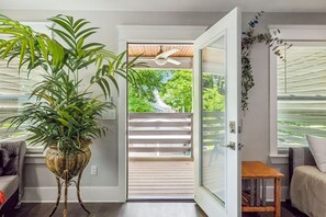 A room with a potted plant, a ceiling fan, a sliding glass door leading to a deck, and a small wooden table. - Stay in style! Spacious Nash home near Broadway! (Nashville)