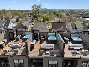 Eine Dachterrasse mit mehreren Whirlpools und Sitzbereichen im Freien.