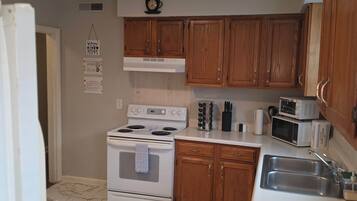 A kitchen with wooden cabinets, a white stove, a microwave, and a sink.
