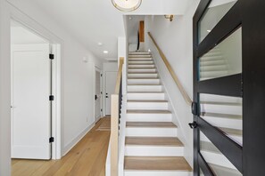 Eine Treppe mit Holzdielen und einer schwarzen Tür mit Glasfenstern.
