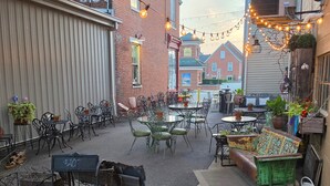 Un espace extérieur aménagé en terrasse, avec des tables et des chaises, entouré d’immeubles.