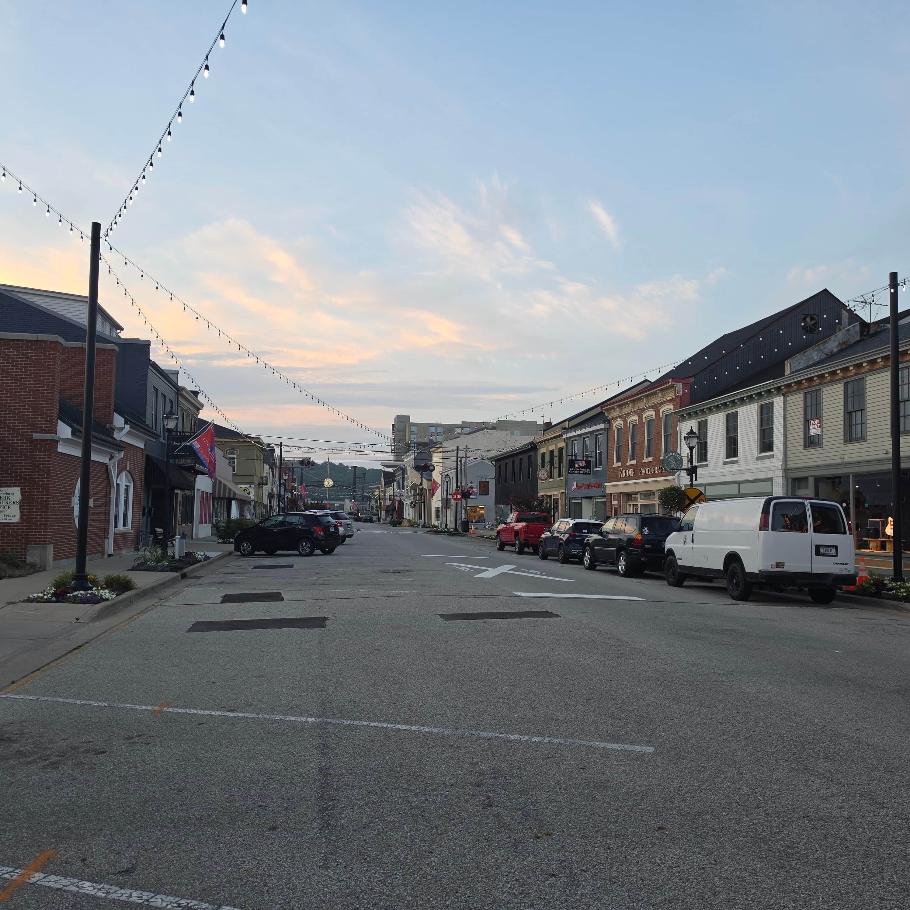 A street lined with buildings, some with signs, and parked cars.
