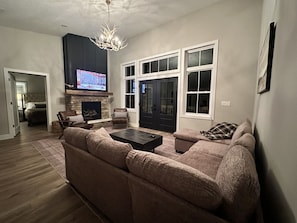 Ein Wohnzimmer mit Ecksofa, Kamin, Fernseher und einem großen Fenster.