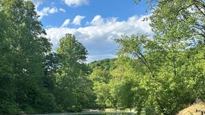 A wooden dock extending into a calm river surrounded by dense green trees. - Brand new creekside home with hot tub, private dock and boat ramp! (Gallipolis)