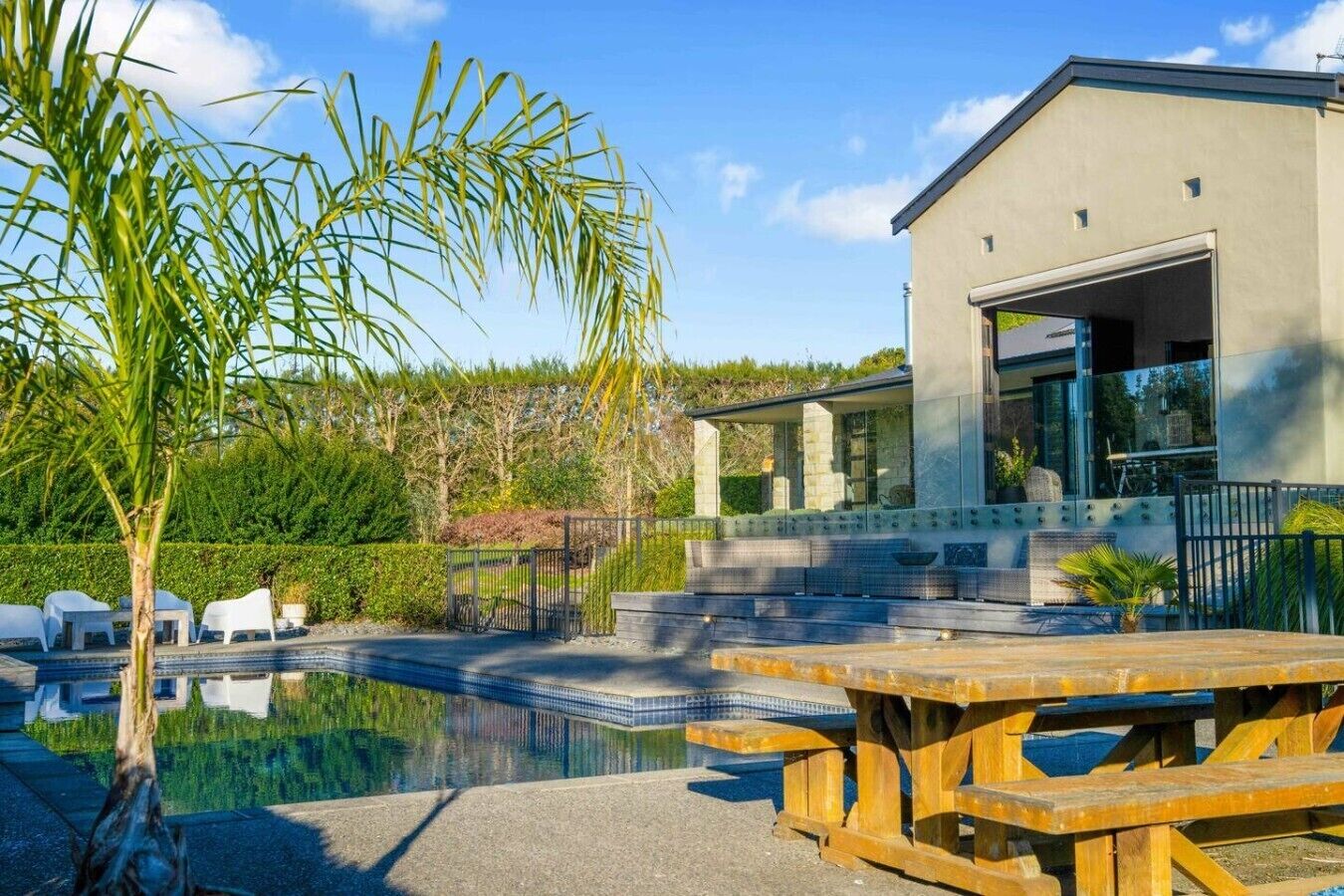 A modern building with a swimming pool, outdoor seating, and a covered patio area.