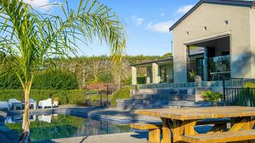 A modern building with a swimming pool, outdoor seating, and a covered patio area.