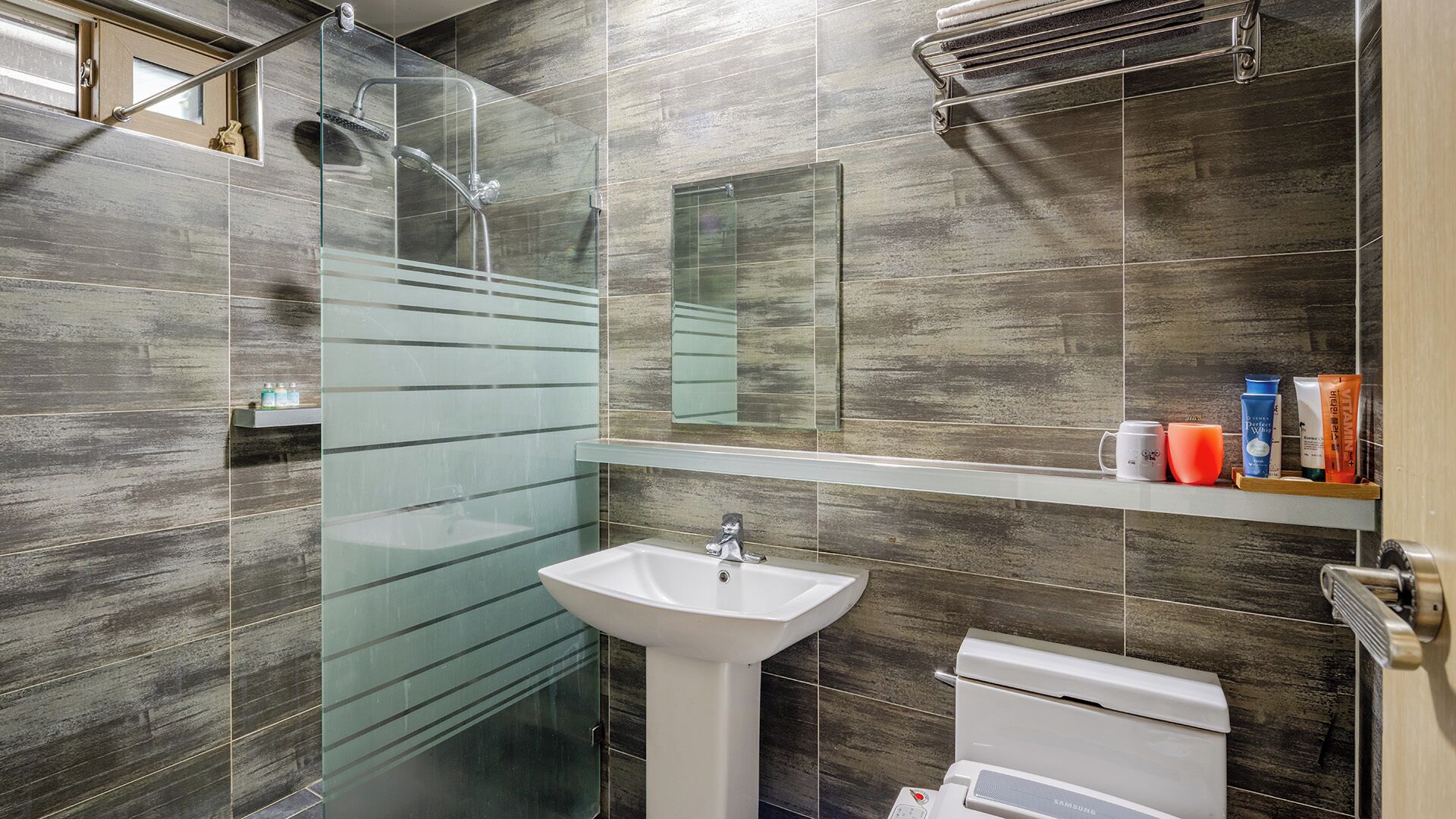 A modern bathroom with a glass shower enclosure, a white sink, and a toilet.