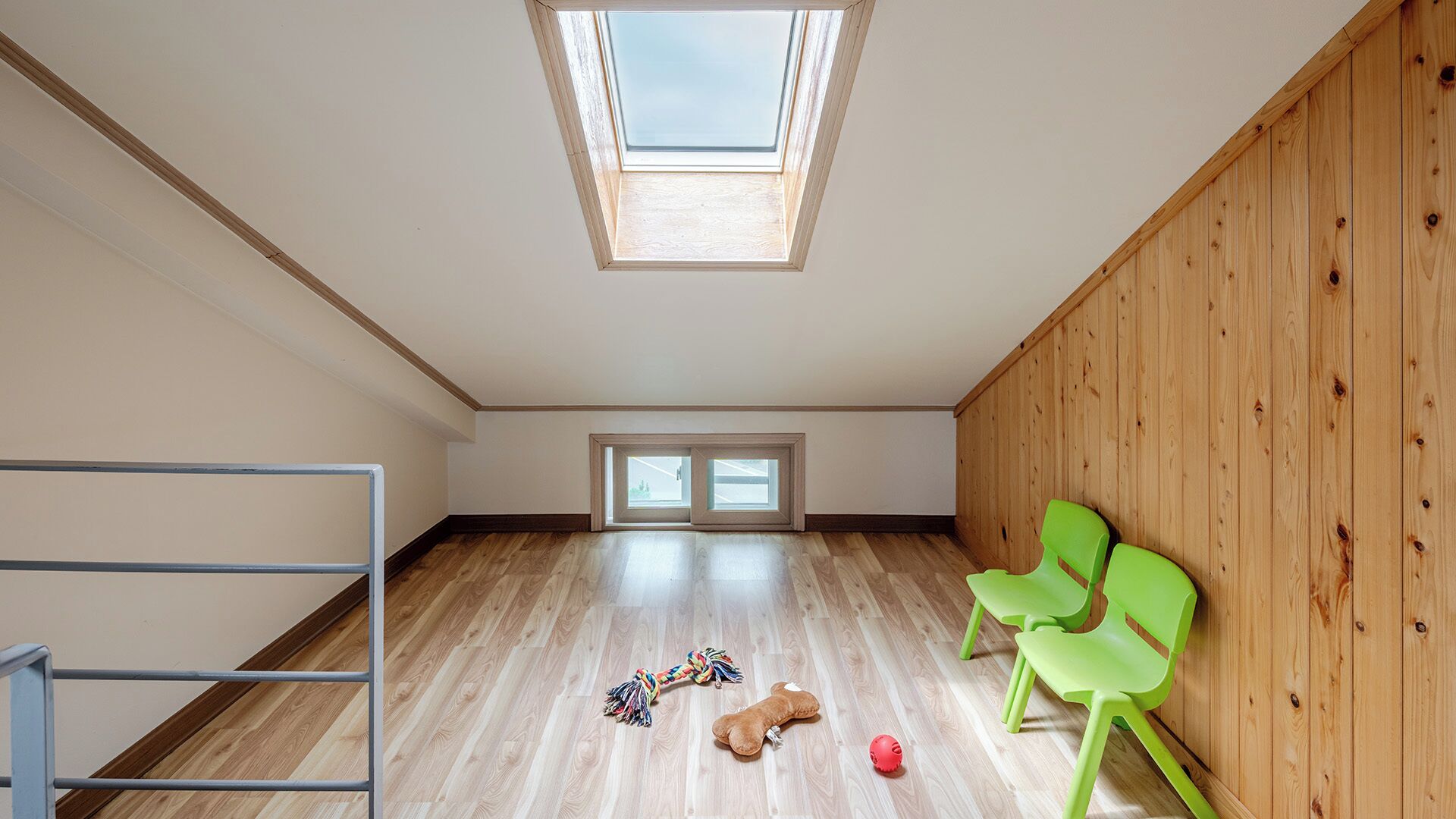 A room with a skylight, wooden walls, a metal ladder, and two windows.