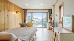Habitación de hotel con cama, escritorio, televisor y balcón con vistas.
