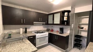 A kitchen with dark cabinets, a white stove, and a countertop with a coffee maker and blender. - 70ft from the Tiffany's store in Polanco, near the World Cup, 2-bedroom apartment with a balcony. (Ciudad de México)