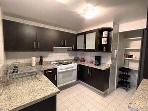 Eine Küche mit dunklen Schränken, einem weißen Herd und einer Arbeitsplatte mit Kaffeemaschine und Mixer.